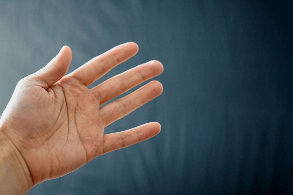 Adult hand with Raynaud's Syndrome - Phenomenon. Close up hand with fingers on dark background with copy space